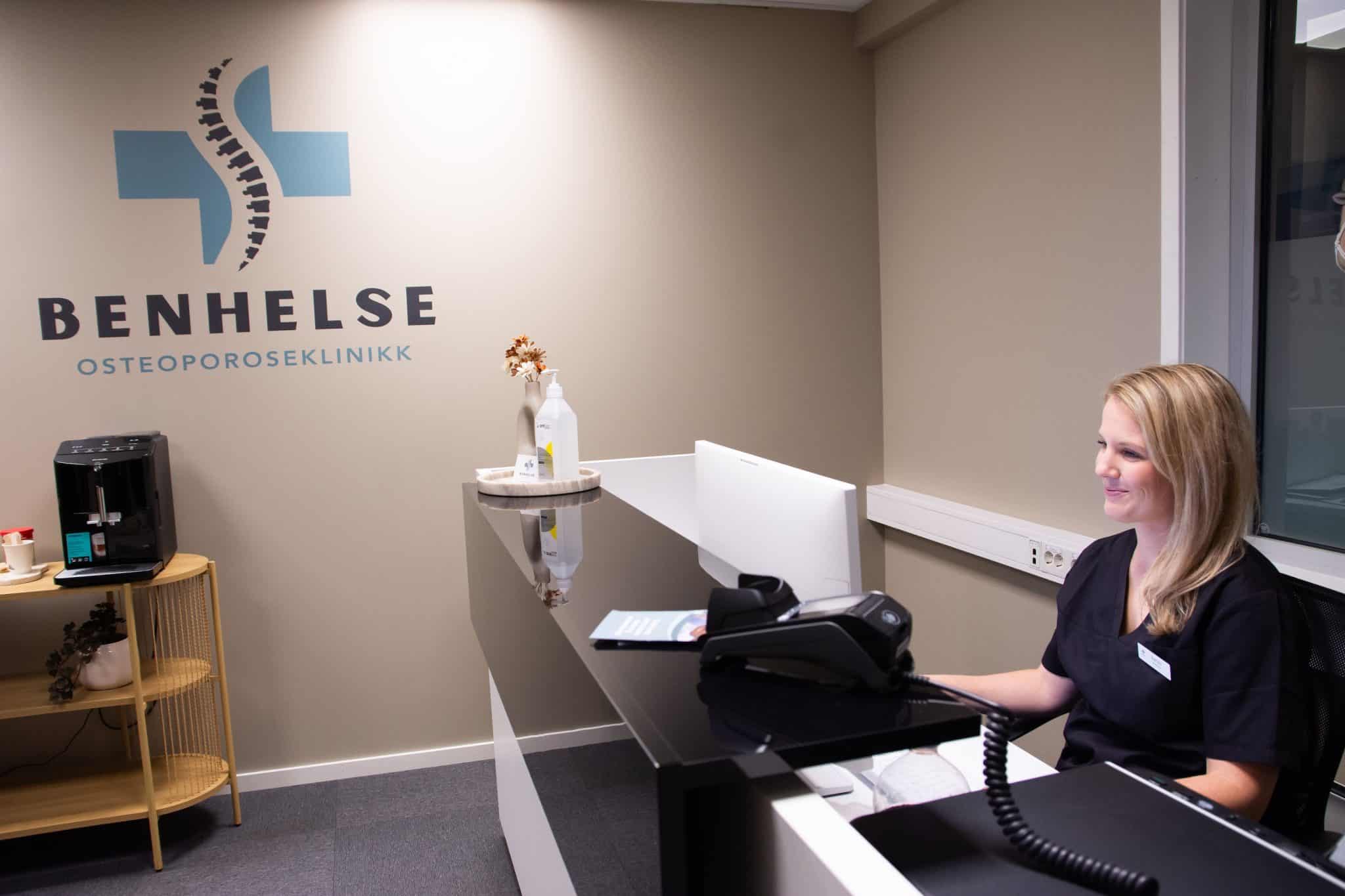 Sykepleier Karine sitter i resepsjonen hos Benhelse, osteoporoseklinikken i Sarpsborg